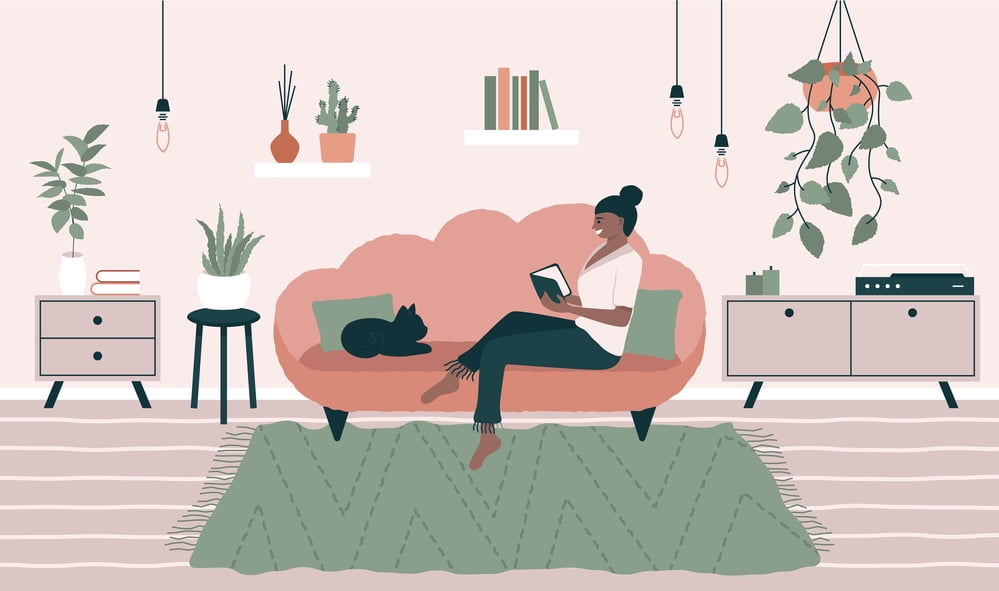 Introvert woman sitting on her couch with her cat and reading a book