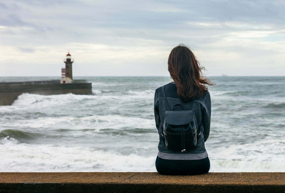 Introverted woman sitting alone at the ocean
