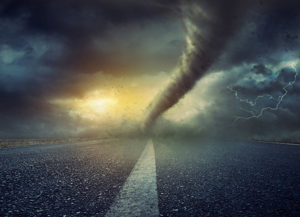 Devastating tornado twisting on a road with dark clouds and lightning