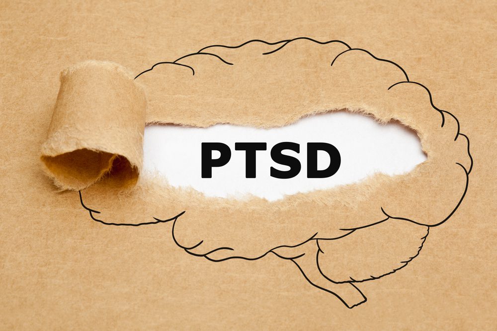 Acronym of post-traumatic stress disorder (PTSD) appearing behind torn brown paper in human brain concept